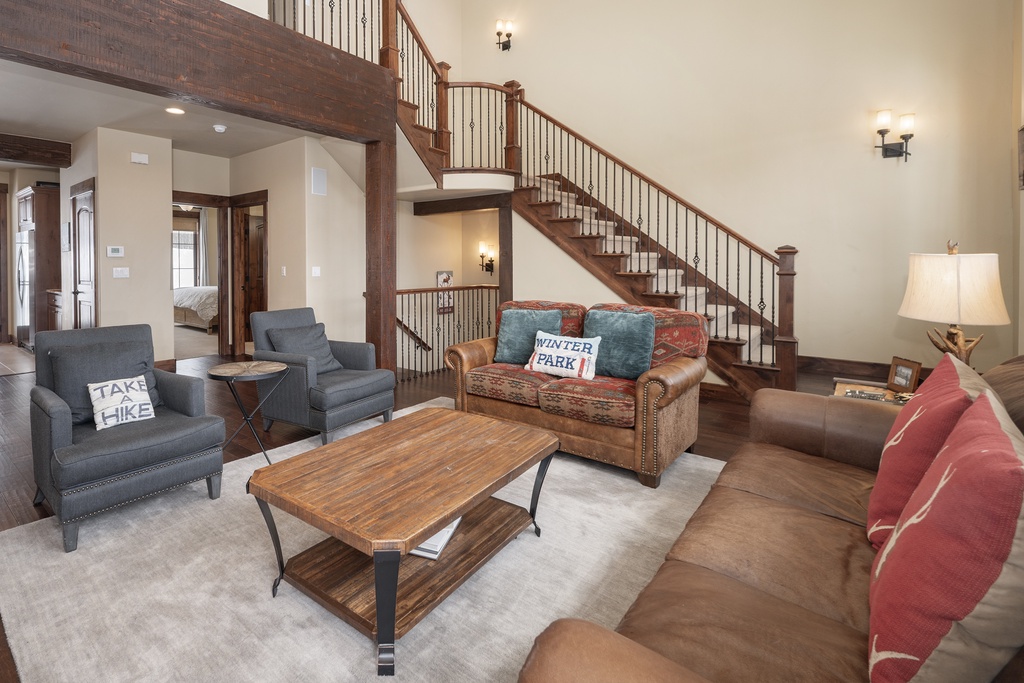 Relax in your spacious living room with comfortable seating, rustic wood beams, and a stunning two-story layout that creates an inviting mountain retreat atmosphere.