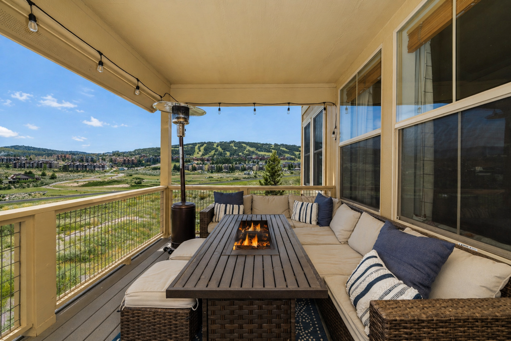 Cozy up around your private fire table on this covered balcony, where mountain views and twinkling lights create the perfect evening retreat.