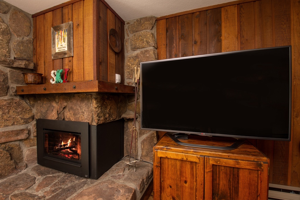 Cozy up by your crackling fireplace while watching your favorite shows on the large flat-screen TV in this rustic living space.