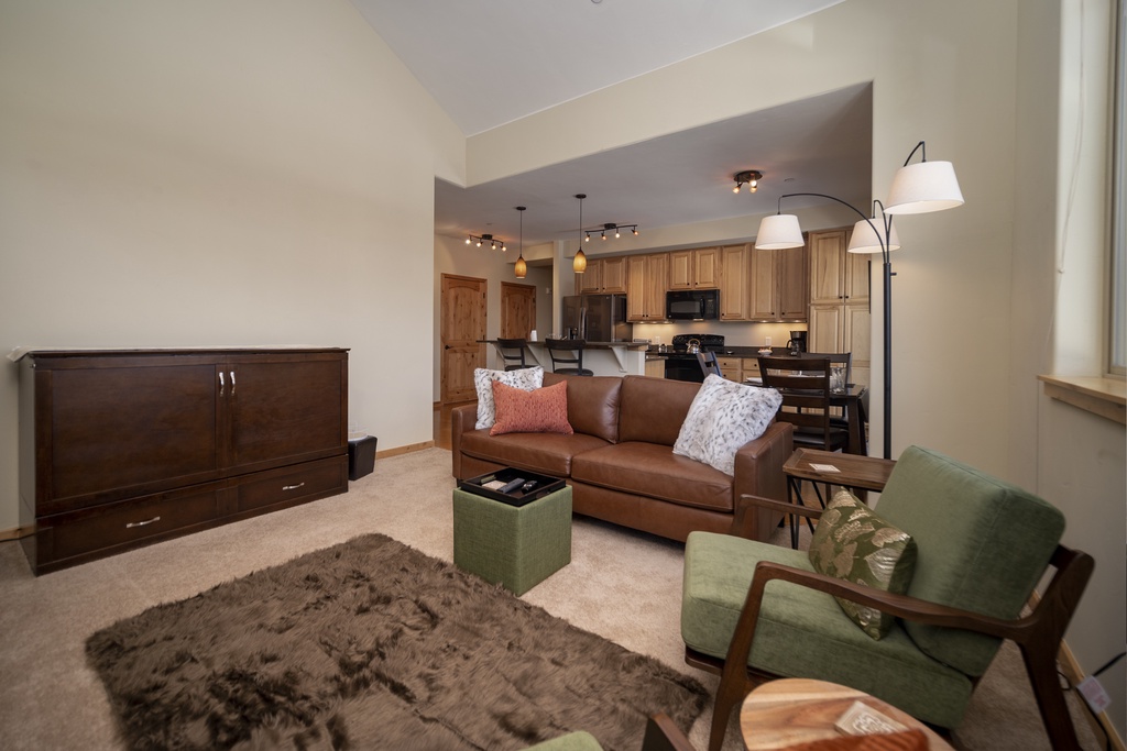 Sink into plush leather seating surrounded by warm wood tones and modern lighting in your stylish open-concept living space.