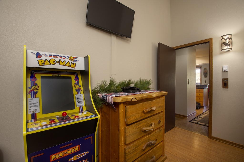 Unwind in your game room with vintage Pac-Man arcade fun, wall-mounted TV for movie nights, and rustic storage for all your belongings.