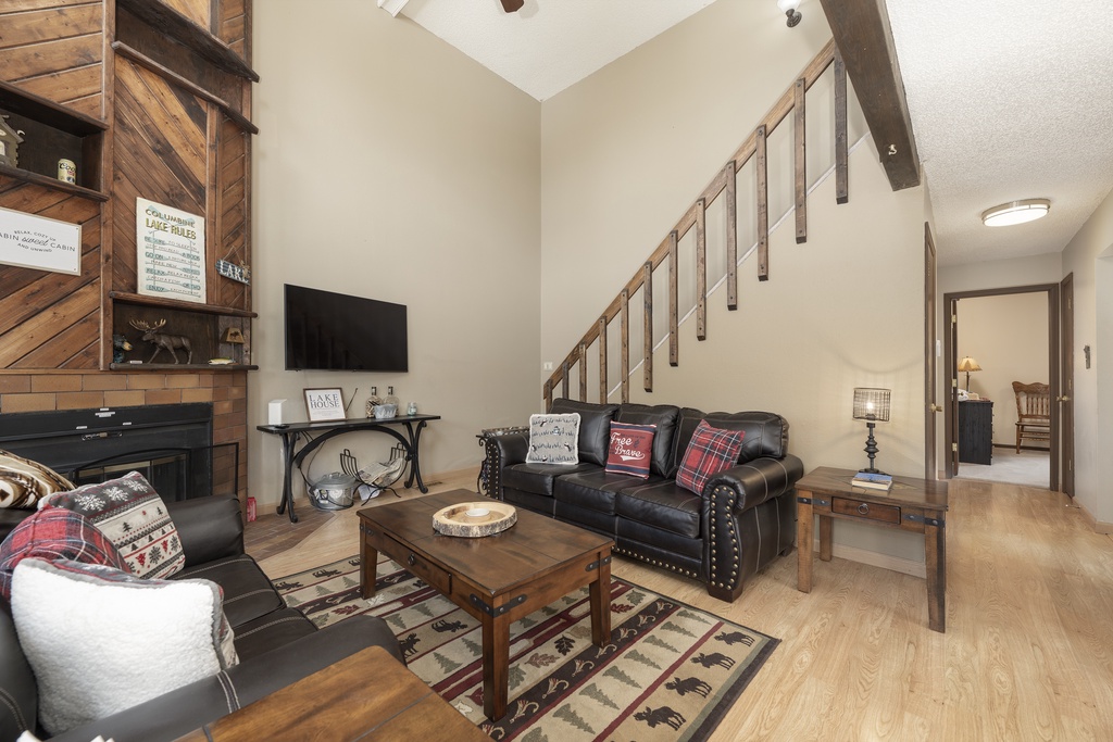 Unwind in your rustic living room featuring leather seating, a cozy fireplace, and charming cabin-style décor that makes relaxation effortless.