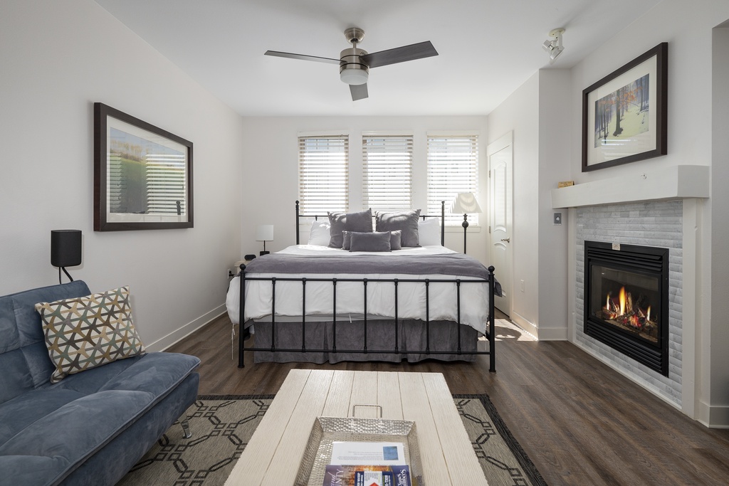 Unwind in your cozy suite where a crackling fireplace meets modern comfort, complete with plush seating and elegant furnishings for ultimate relaxation.