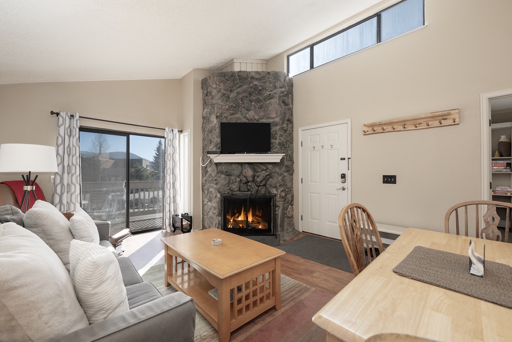 Cozy up by your crackling stone fireplace while enjoying mountain views through expansive windows in this inviting living space.