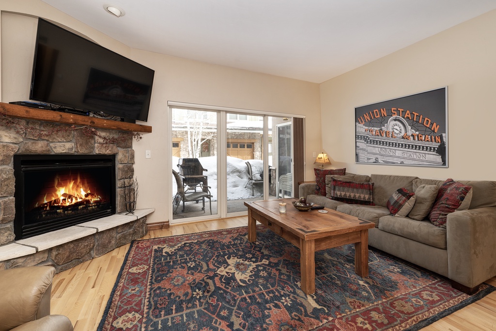 Cozy up by the crackling fireplace in your comfortable living room, where mountain warmth meets modern comfort for perfect après-ski relaxation.