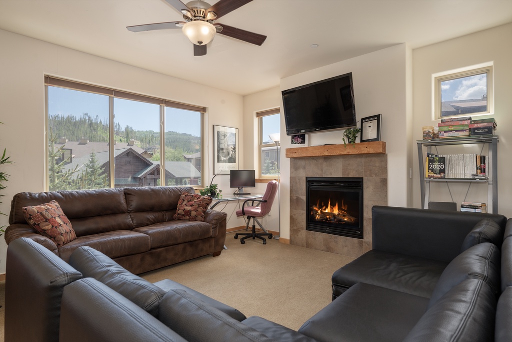 Cozy up in your spacious living room with leather seating, crackling fireplace, and stunning mountain views through expansive windows.