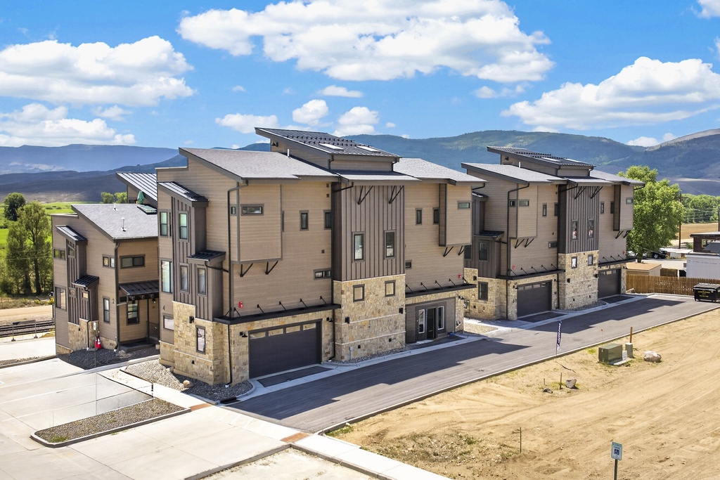 Contemporary townhome complex situated in a scenic mountain valley with rolling hills in the distance.