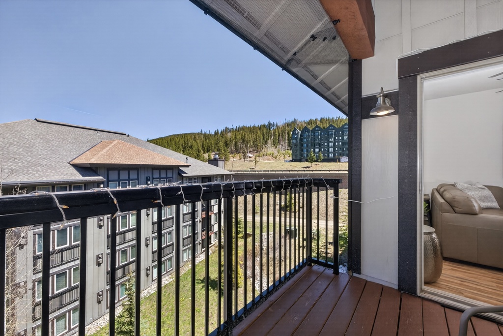 The balcony provides a scenic view of forested hillsides and nearby buildings, blending comfort with natural beauty—perfect for your morning coffee or evening unwind.