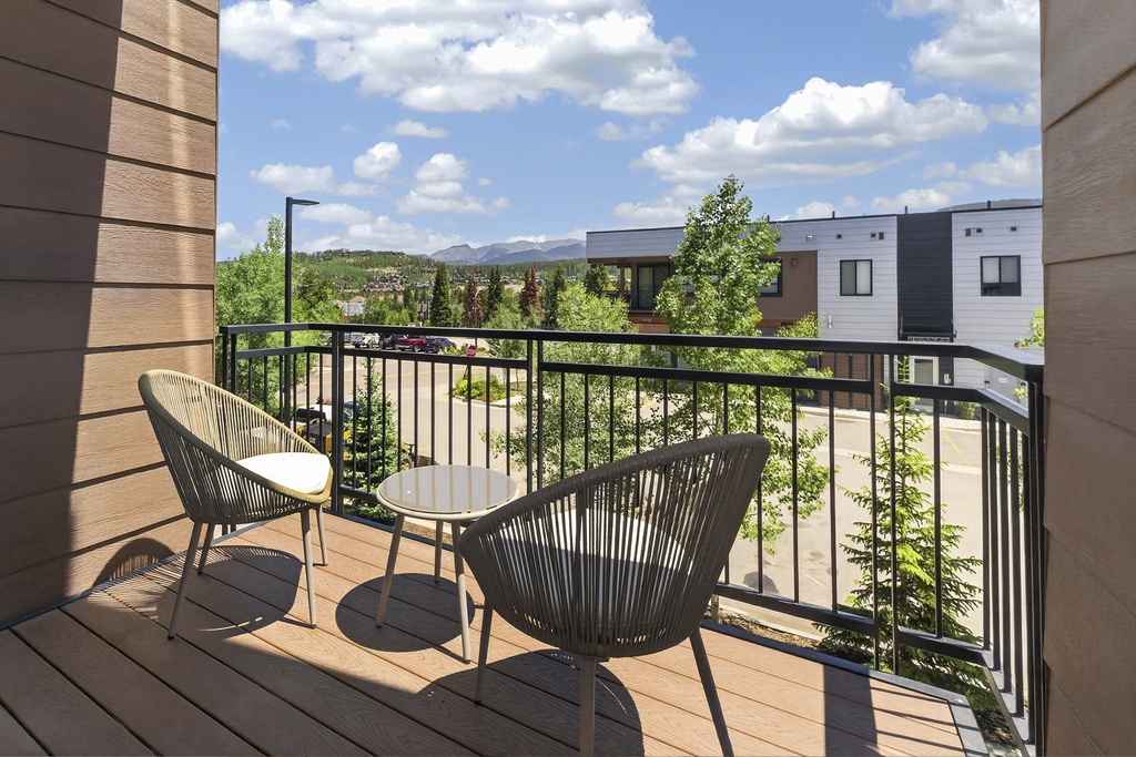 Step onto your private balcony and unwind in modern seating while taking in mountain and neighborhood views under bright skies—a peaceful retreat awaits.