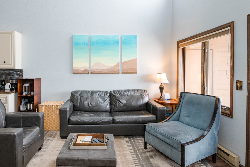 Sink into plush leather seating in your stylish living space, where mountain artwork and warm lighting create the perfect atmosphere for unwinding.