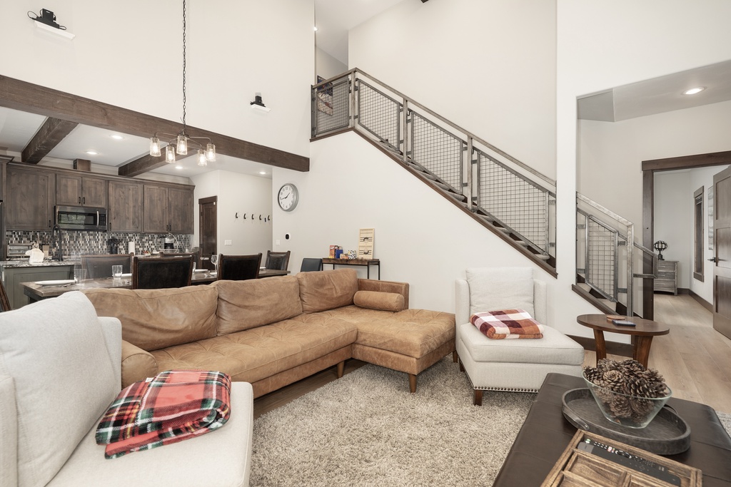 Relax in your stylish open-concept living space with soaring ceilings, exposed beams, and cozy seating perfect for unwinding after mountain adventures.