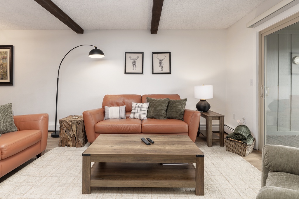 Unwind in your stylish living room with rich leather seating, exposed beams, and thoughtful touches that create the perfect mountain retreat atmosphere.