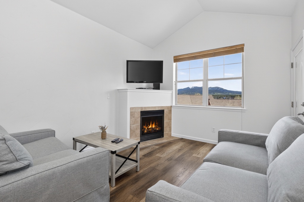 Unwind in your bright living room with vaulted ceilings, a warm fireplace, and stunning mountain views framed by large windows.