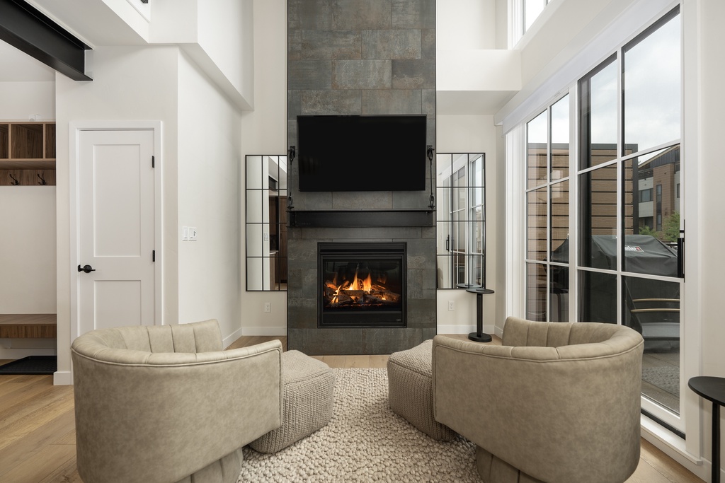 Settle into plush seating around your cozy fireplace, where crackling flames and soaring ceilings create the perfect evening retreat.