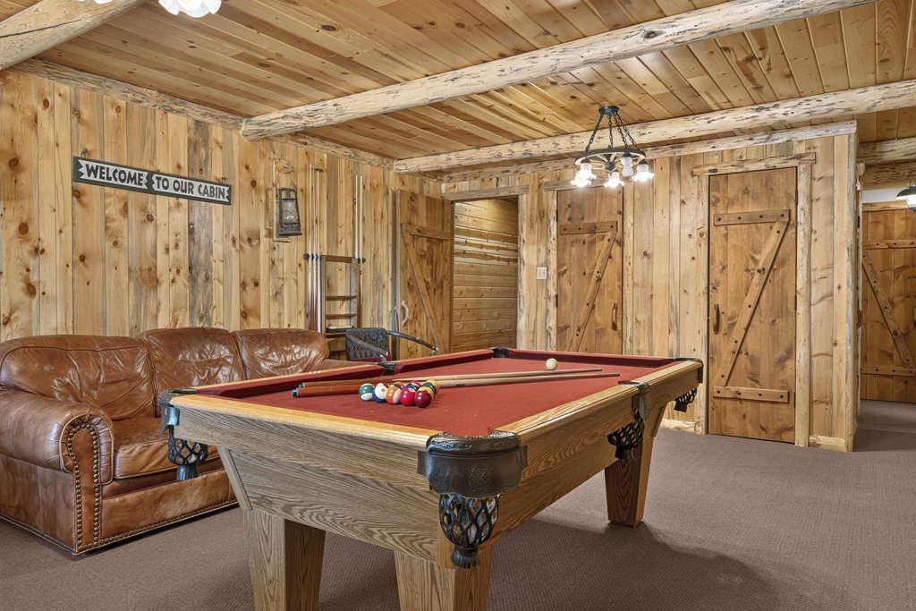 Challenge your group to a friendly game of pool in this cozy cabin game room, complete with rustic wood beams, plush leather seating, and a welcoming mountain lodge atmosphere.