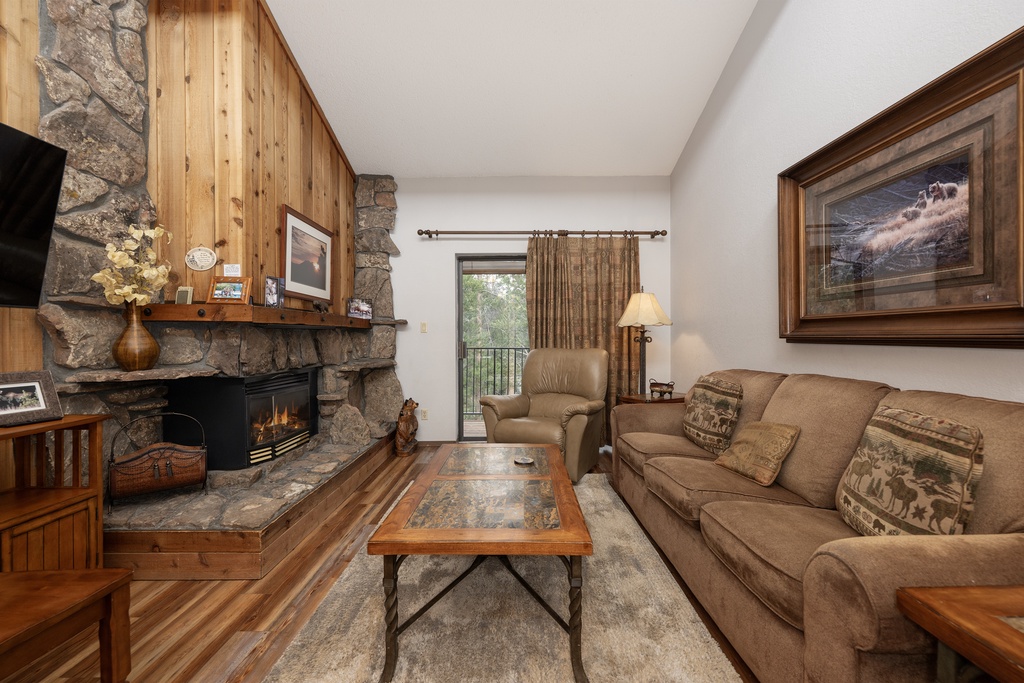 Relax by your stone fireplace while enjoying mountain views from your private balcony in this cozy living space.
