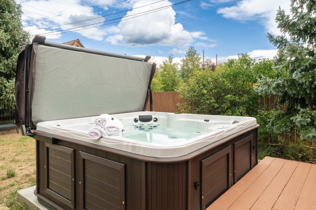 Slip into your private hot tub oasis, complete with fluffy towels, surrounded by lush greenery for ultimate relaxation.