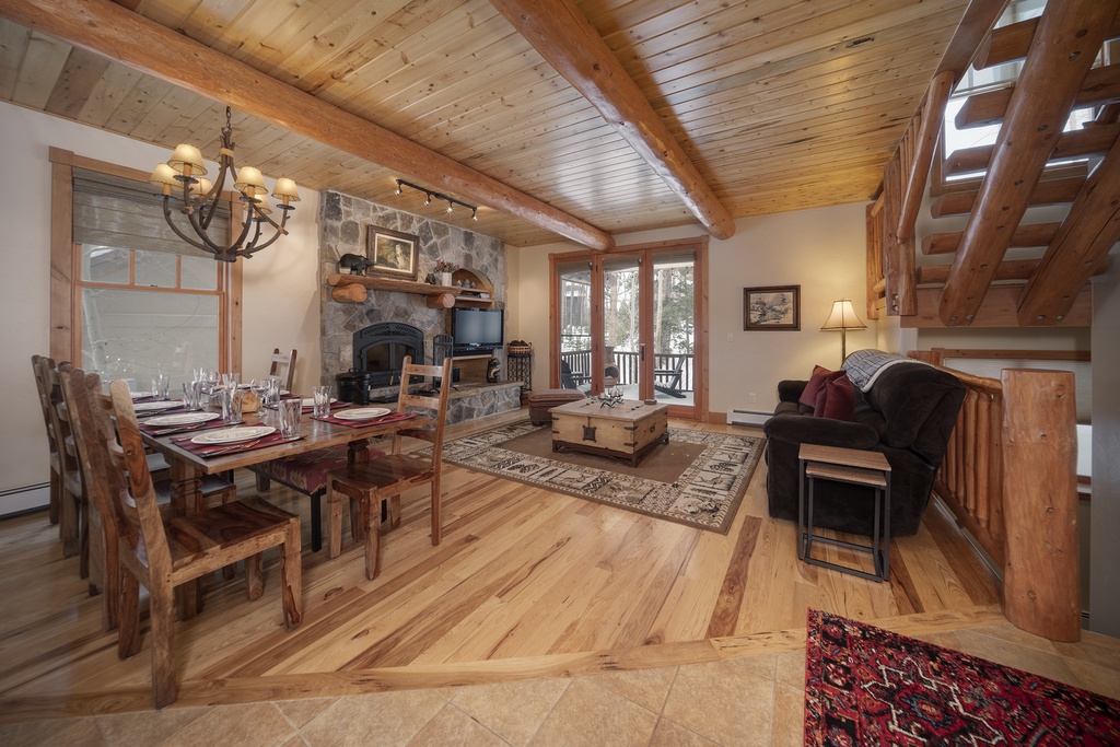 Cozy up by your stone fireplace in this rustic living space, where exposed beams and warm wood create the perfect mountain retreat atmosphere.