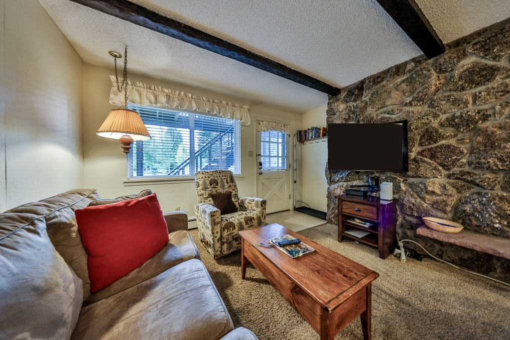 Cozy up in your rustic living room with exposed stone walls, plush seating, and warm wood accents creating the perfect mountain retreat atmosphere.