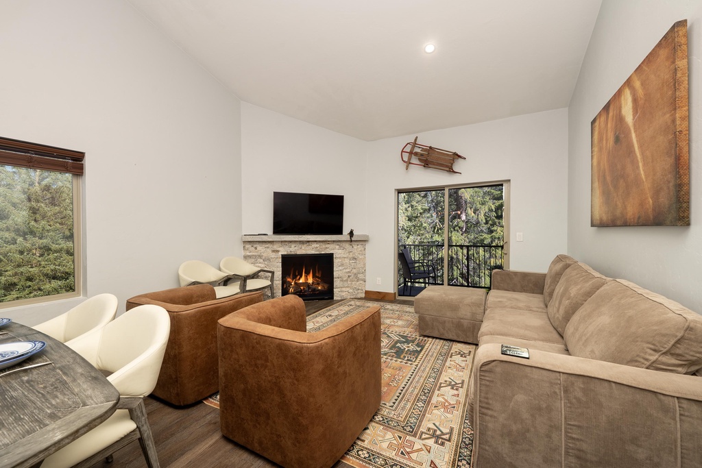 Sink into plush seating by your crackling fireplace, where forest views and cozy warmth create the perfect retreat.