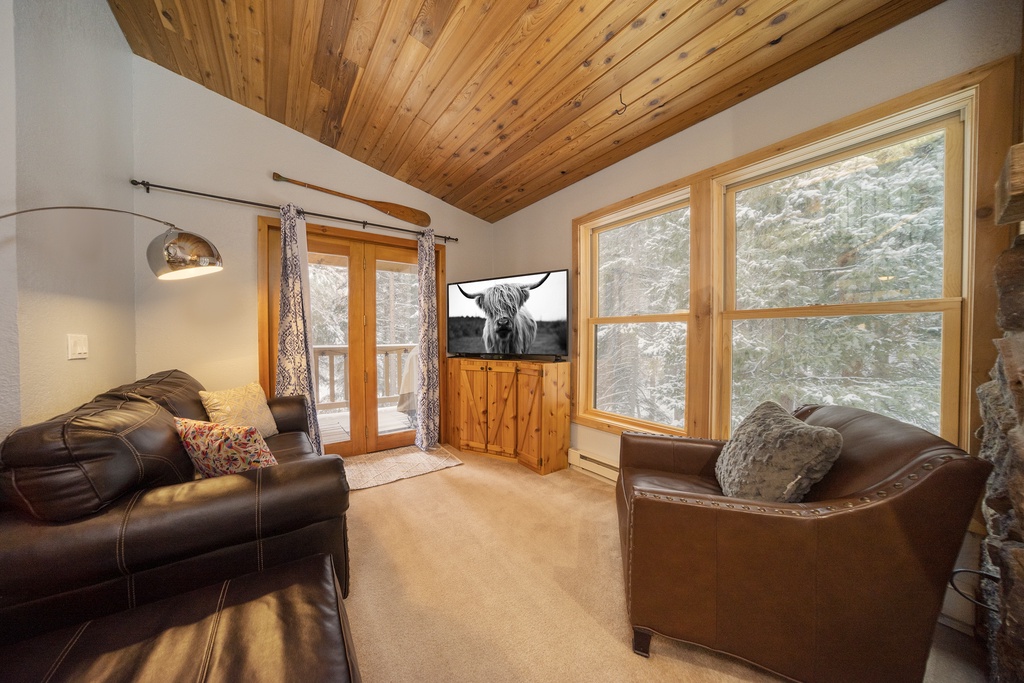 Sink into plush leather seating while natural light streams through expansive windows, creating your perfect retreat beneath warm wood ceilings.