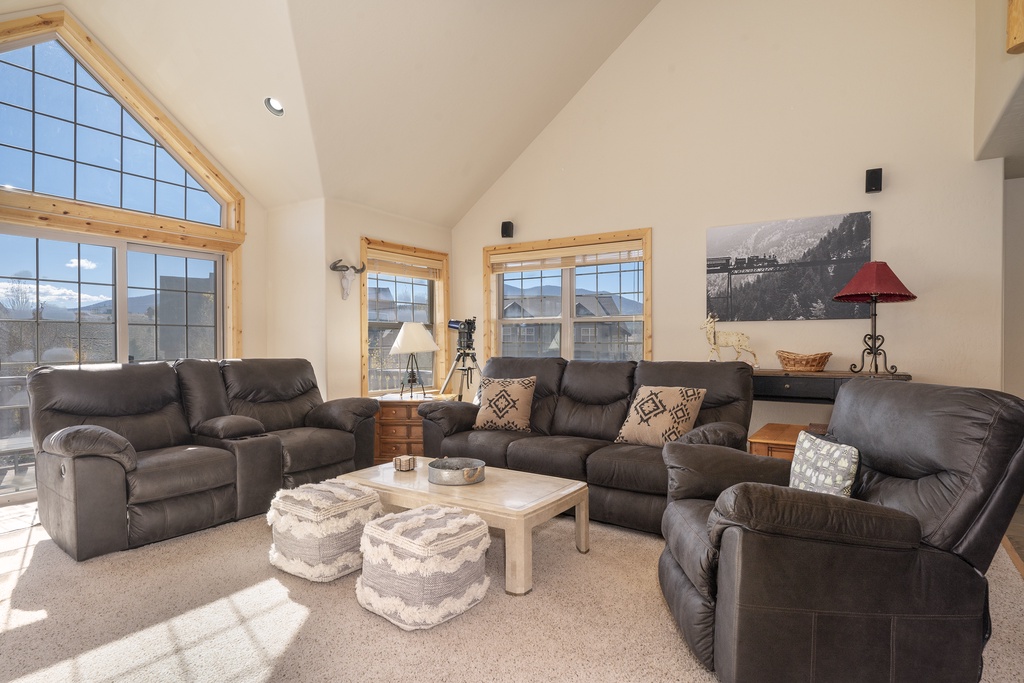 Relax in your spacious living room with plush leather seating and mountain views through soaring windows.