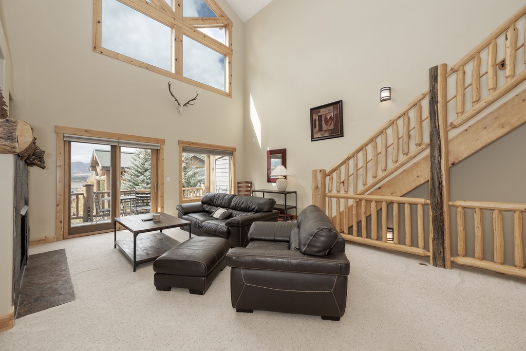 Relax in your spacious living room with soaring ceilings, leather seating, and natural light streaming through mountain-view windows.