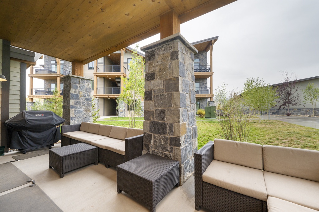 Your private patio features comfortable outdoor seating around a striking stone pillar, perfect for morning coffee or evening relaxation.