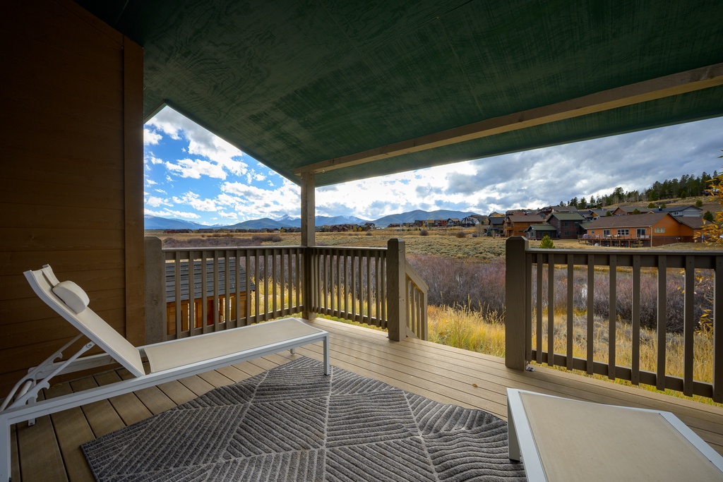 Covered deck with mountain views and open grasslands framing the property's natural setting—ideal for outdoor relaxation in this secluded retreat.
