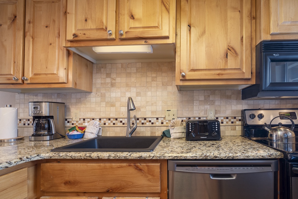 You'll love cooking in this fully equipped kitchen with warm wood cabinets, granite counters, and modern appliances ready for your culinary adventures.