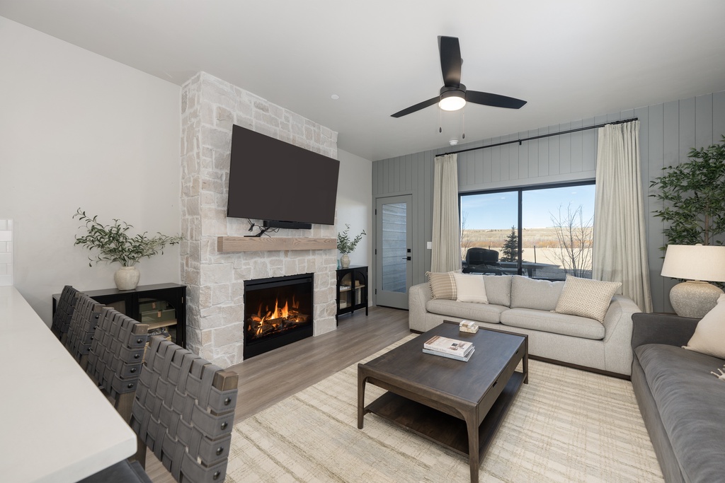Unwind in your cozy living room where a crackling fireplace meets modern comfort, complete with plush seating and serene views.