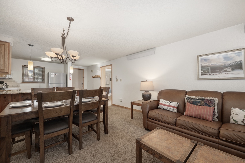 Settle into your spacious open-concept living area where warm leather seating and rustic wood dining create the perfect mountain retreat atmosphere.