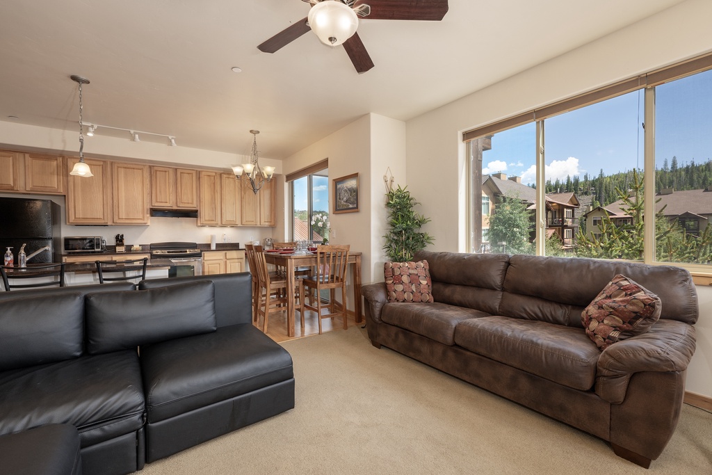 Relax in your spacious living room with leather seating while enjoying stunning mountain views through oversized windows.