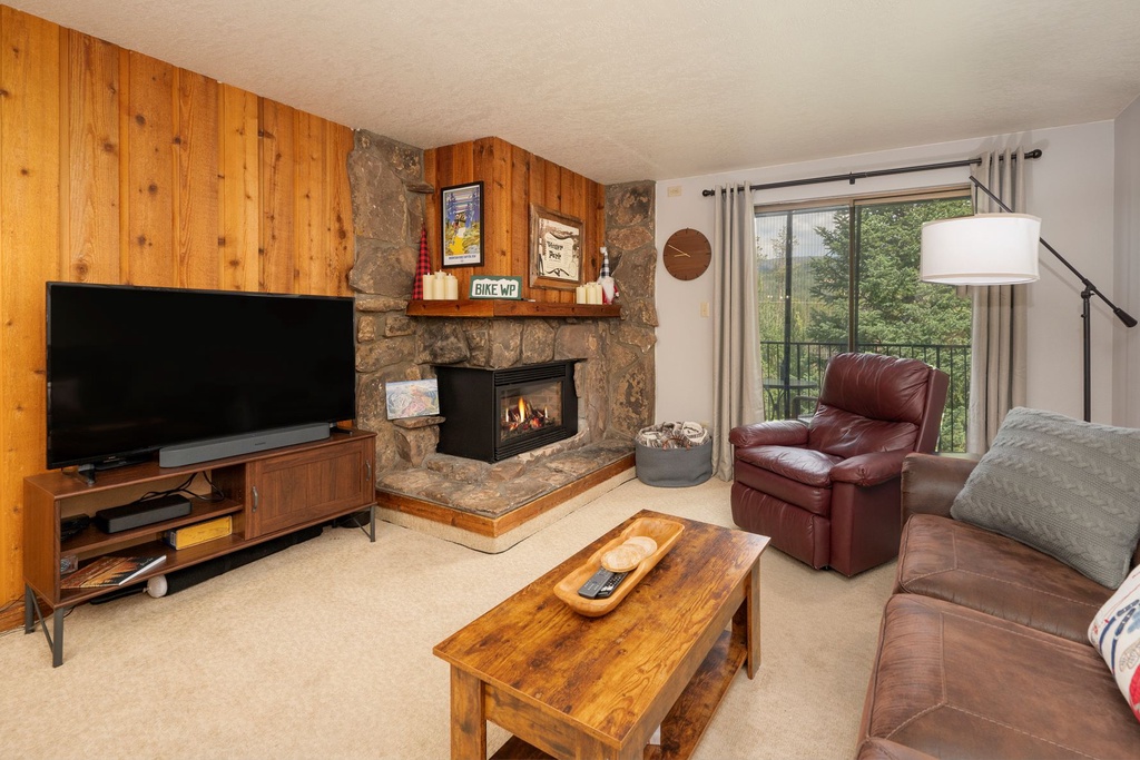 Cozy up by your stone fireplace in this warm living room with leather seating and mountain views through the balcony doors.