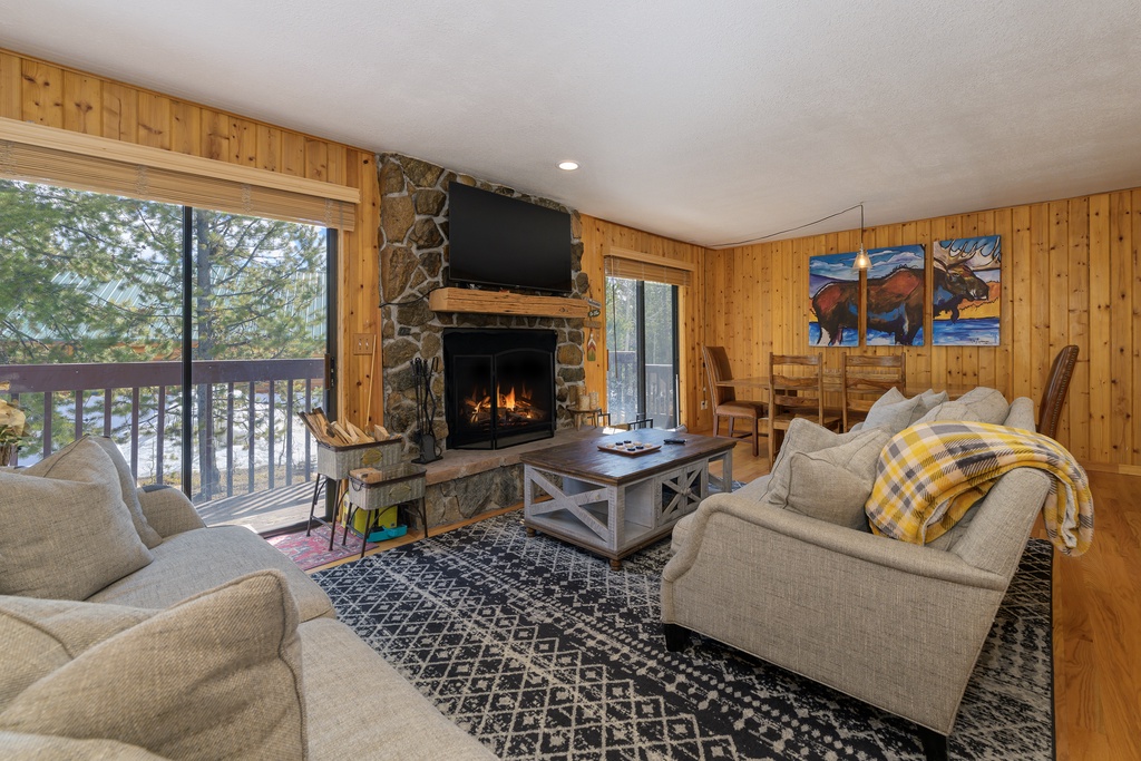 Cozy up in your rustic living room where warm wood surrounds you, a stone fireplace crackles, and your private balcony offers peaceful views.