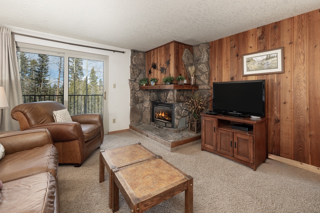 Cozy up by your crackling fireplace while watching TV, surrounded by rustic wood paneling and mountain views from your private balcony.