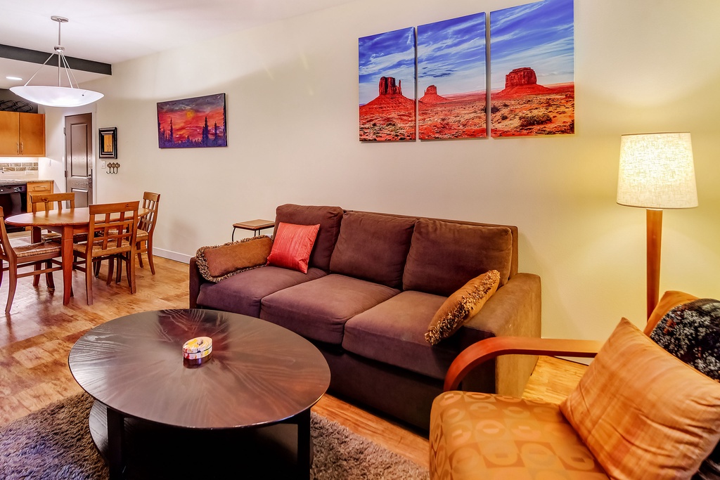 Sink into the cozy sofa and unwind in your inviting living space, where warm wood tones and desert-inspired art create a relaxing home-away-from-home atmosphere.