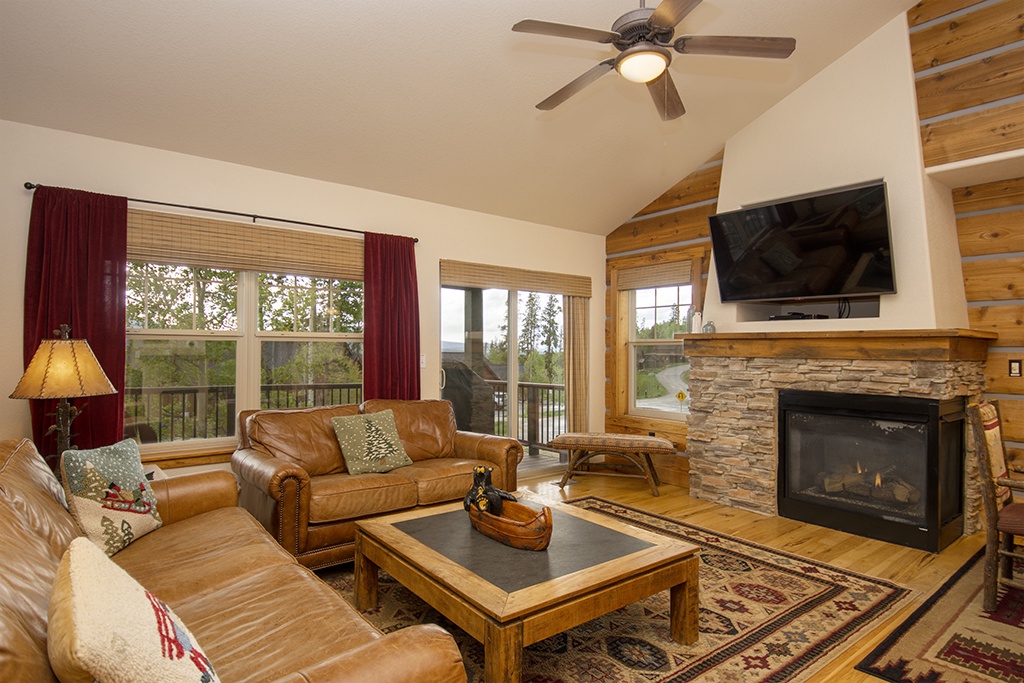Sink into plush leather seating by the warm stone fireplace, where your mountain retreat comes alive with rustic elegance and modern comfort.