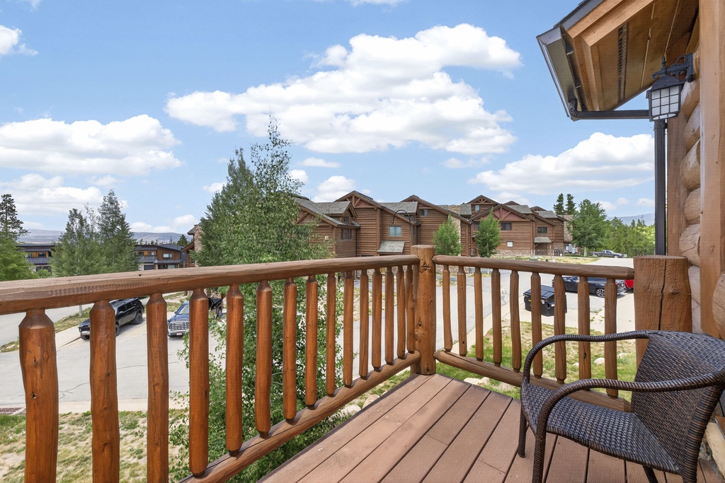 A scenic mountain property surrounded by trees and neighboring buildings, with parking visible below. The log cabin-style architecture adds rustic charm to this peaceful setting.
