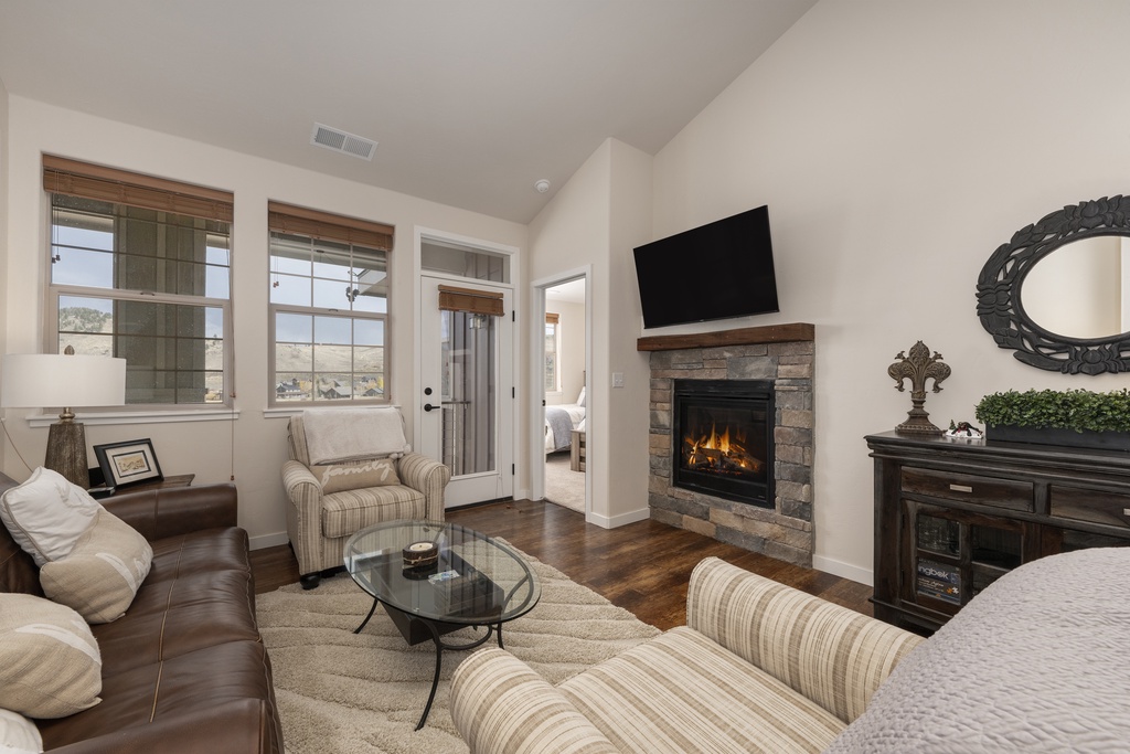 Cozy up in your spacious living room with a warm stone fireplace, plush seating, and elegant decor.