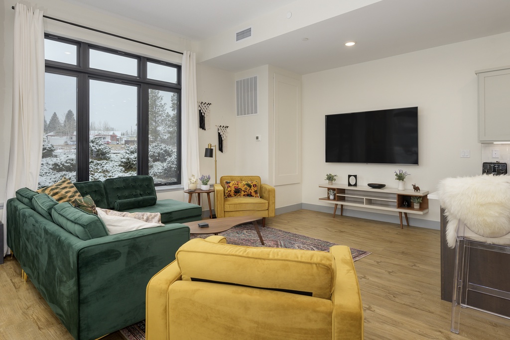 Sink into plush emerald velvet sofas while watching your favorite shows on the wall-mounted TV in this stylish living space.