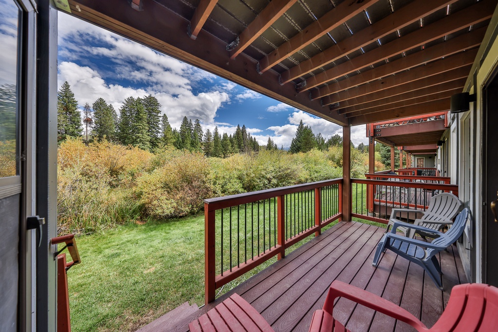 Relax on your private deck overlooking serene forest views, where morning coffee feels perfect under exposed beams.