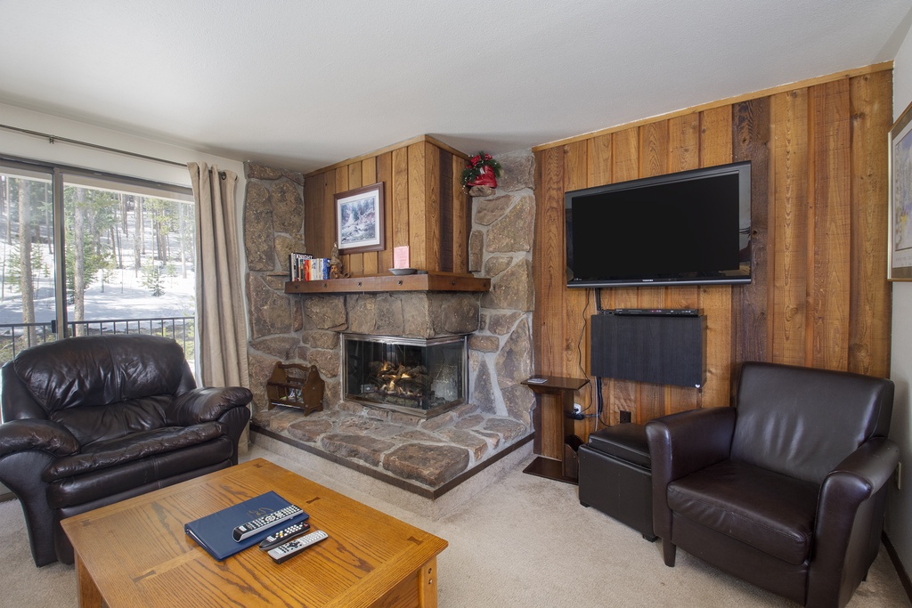 Settle into plush leather seating by your crackling stone fireplace, where warm wood paneling creates the perfect mountain retreat atmosphere.