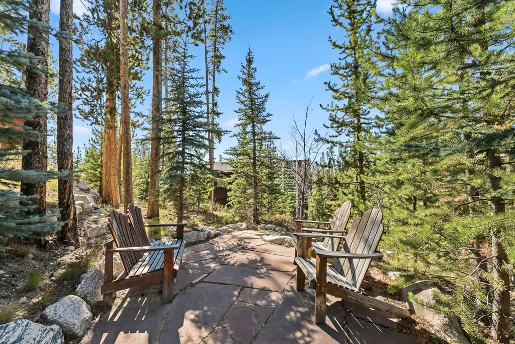 279 Shorewood Drive has a private forest retreat with two Adirondack chairs positioned perfectly for peaceful moments among towering pines and mountain air.