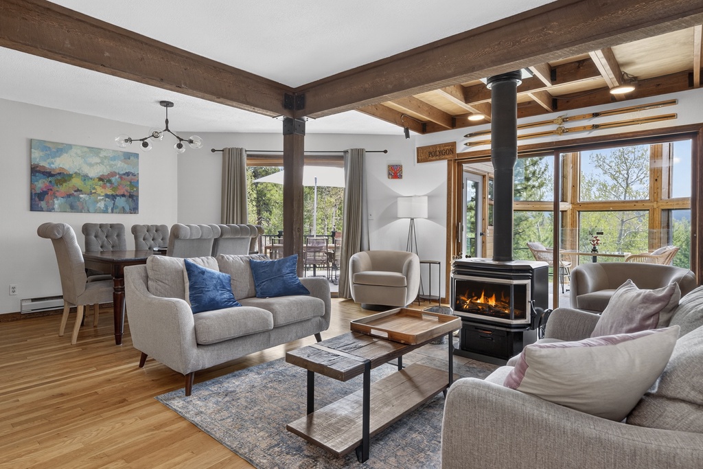 Picture yourself unwinding on the plush sofas, warmed by the fireplace as natural light streams through expansive windows framing stunning mountain and forest views—your perfect retreat awaits.