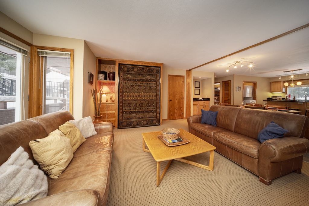 Relax in your spacious living room with rich leather sofas and warm wood accents creating the perfect mountain retreat atmosphere.