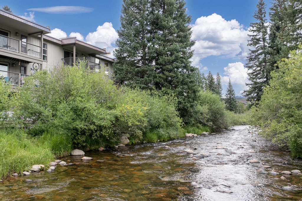 This vacation rental property borders a scenic riverside location with lush evergreens and natural mountain surroundings offering year-round outdoor appeal.