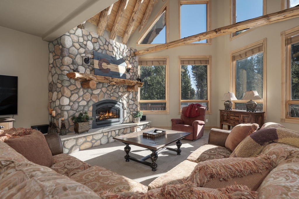 Sink into plush sofas before your crackling stone fireplace, where natural light floods through soaring windows framing mountain views.