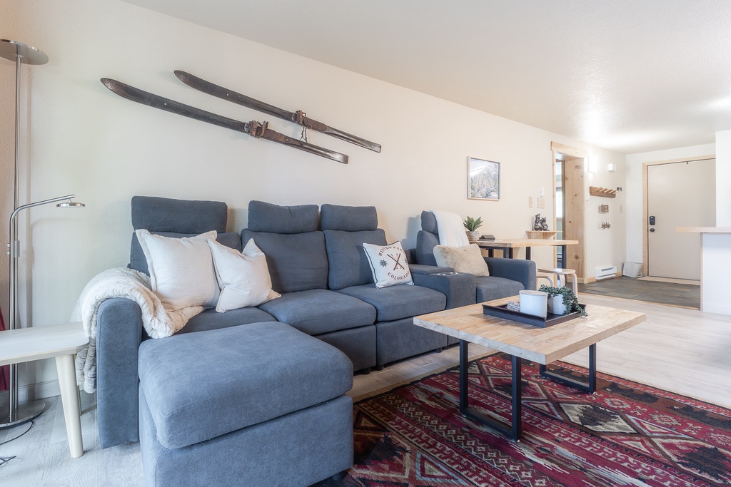 Unwind on the plush sectional sofa while admiring vintage ski decor that adds alpine charm to your bright, modern living space.