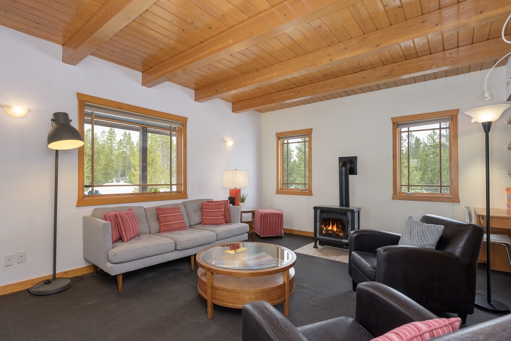 Unwind in your spacious living room with exposed beam ceilings, cozy fireplace, and forest views through large windows.